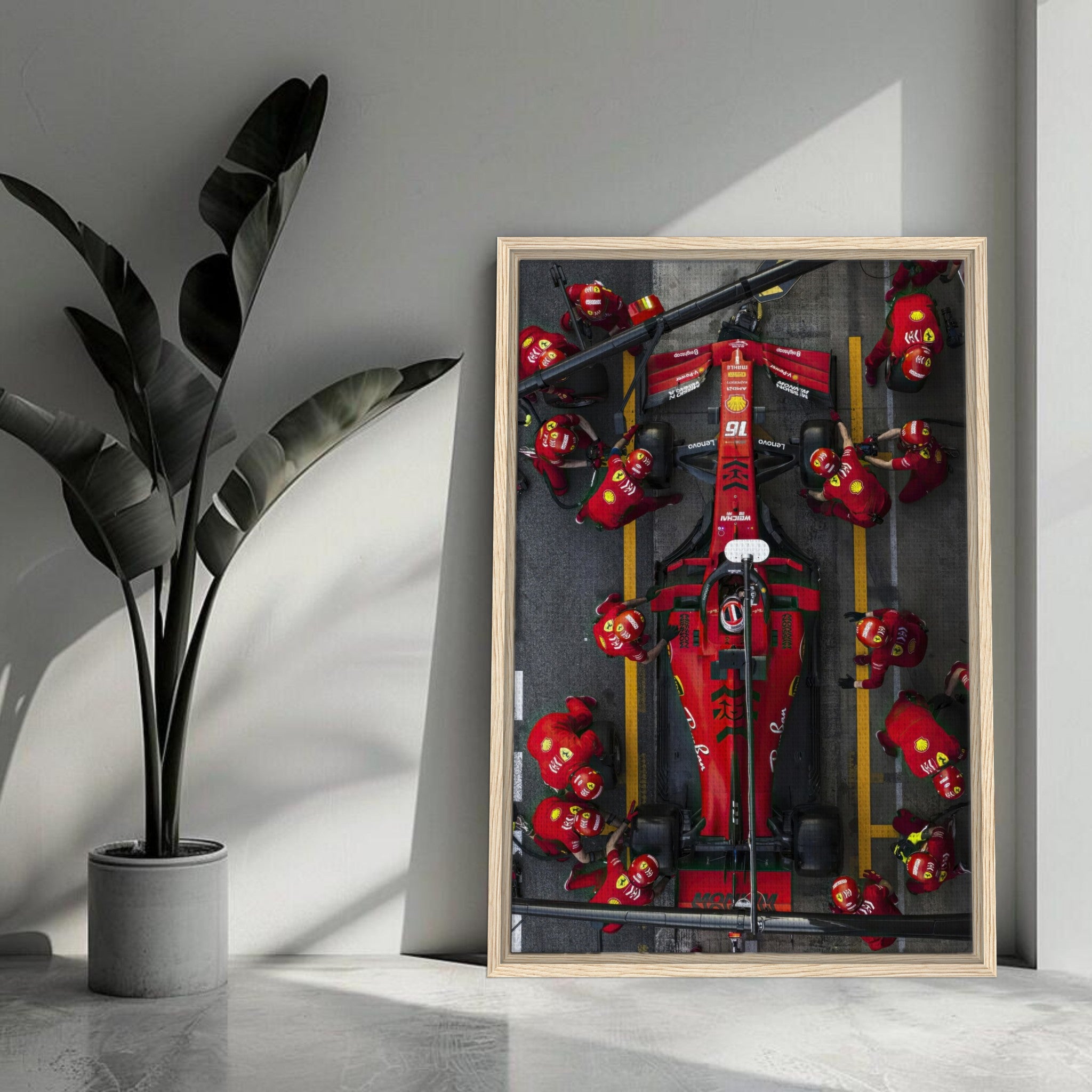 Framed canvas print of a Ferrari Formula 1 pitstop with vibrant colors and dynamic motorsport action in a stylish interior setting.