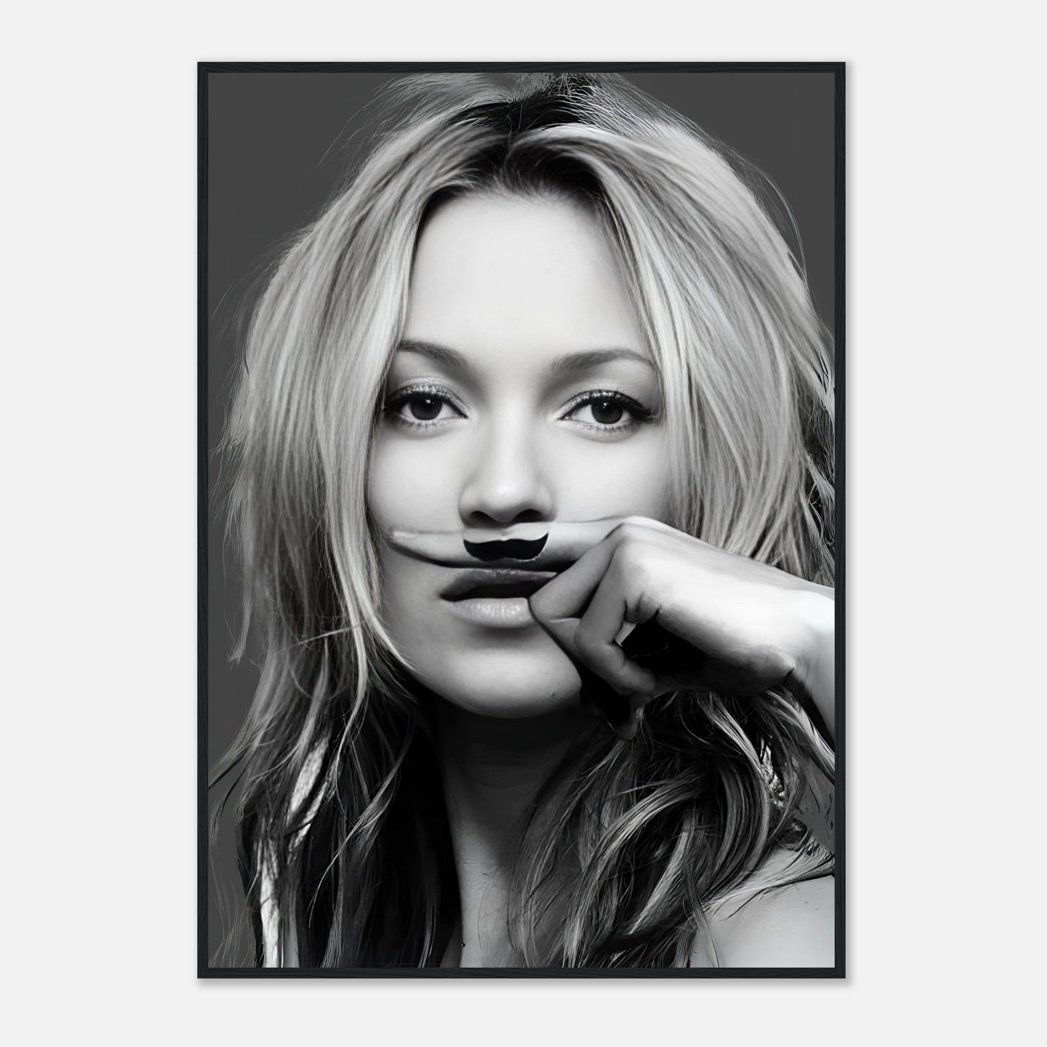 Black-and-white framed print of a woman playfully holding a mustache, adding a whimsical touch to contemporary decor.