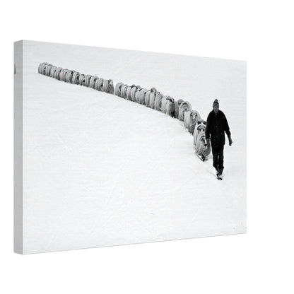 A shepherd walking with a flock of sheep in a serene, snow-covered landscape, captured in black-and-white.