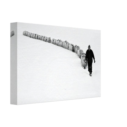 A shepherd walking through a snow-covered landscape, guiding a flock of sheep in a black-and-white canvas print.