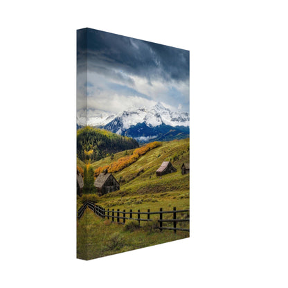 Telluride, Colorado canvas featuring rustic cabins and snow-dusted peaks amidst vibrant autumn foliage and dramatic skies.