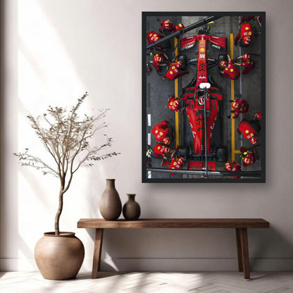 Framed print of a Ferrari Formula 1 pitstop showcasing the race team's dynamic action and vivid red car in a stylish interior setting.