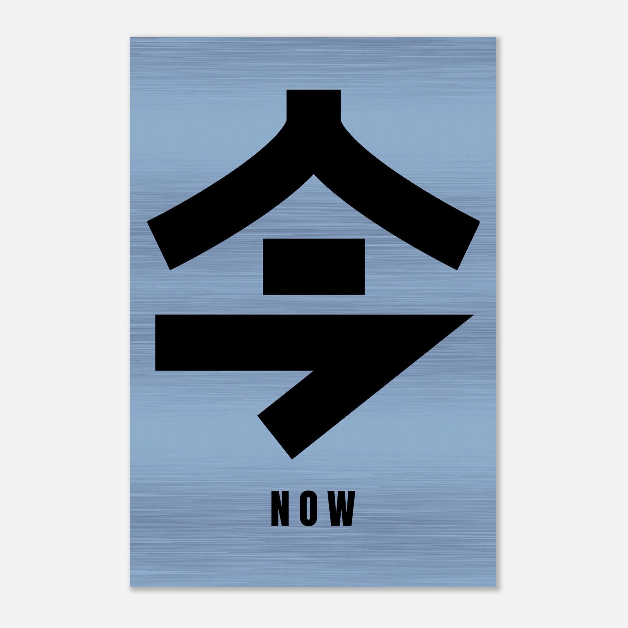 Japanese Kanji for 'Now' printed on brushed metal with bold black characters against a subtle blue background.