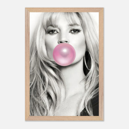 Vintage framed print of Kate Moss blowing pink bubble gum in a striking black-and-white portrait. Perfect for modern decor.