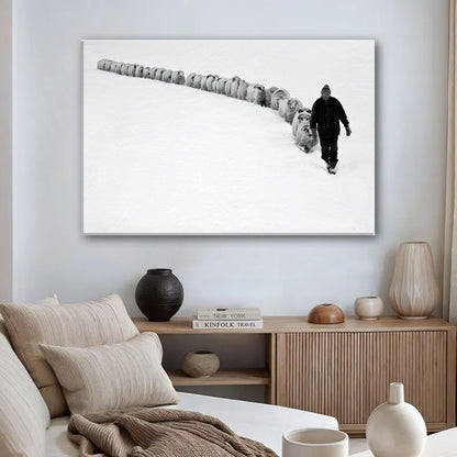A shepherd guiding a flock through a snowy landscape, captured in black-and-white on a canvas print.