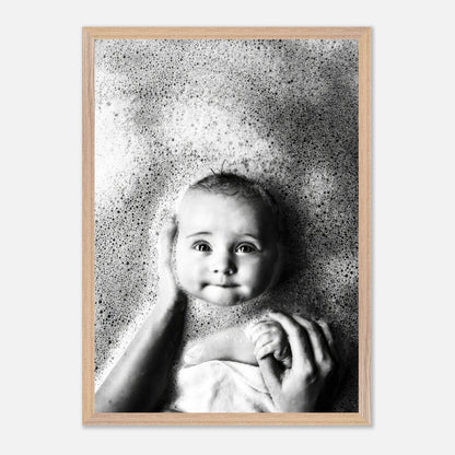 Black-and-white fine art print of a smiling baby surrounded by bubbles during bath time.