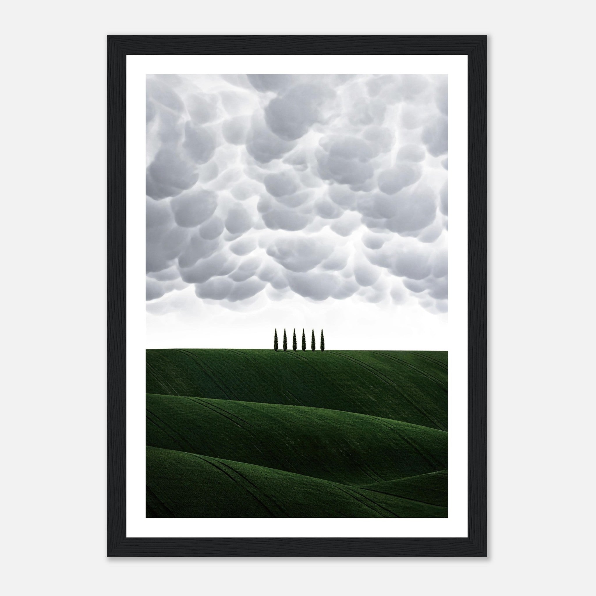 Framed print of Tuscany featuring green hills and cypress trees under dramatic clouds, perfect for elegant decor.