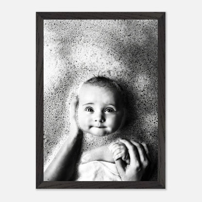 Black and white vintage print of a baby in a bubble bath, exuding innocence and nostalgia, framed elegantly.