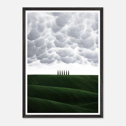 Vintage framed art of Tuscany with green hills and cypress trees under a dramatic sky.