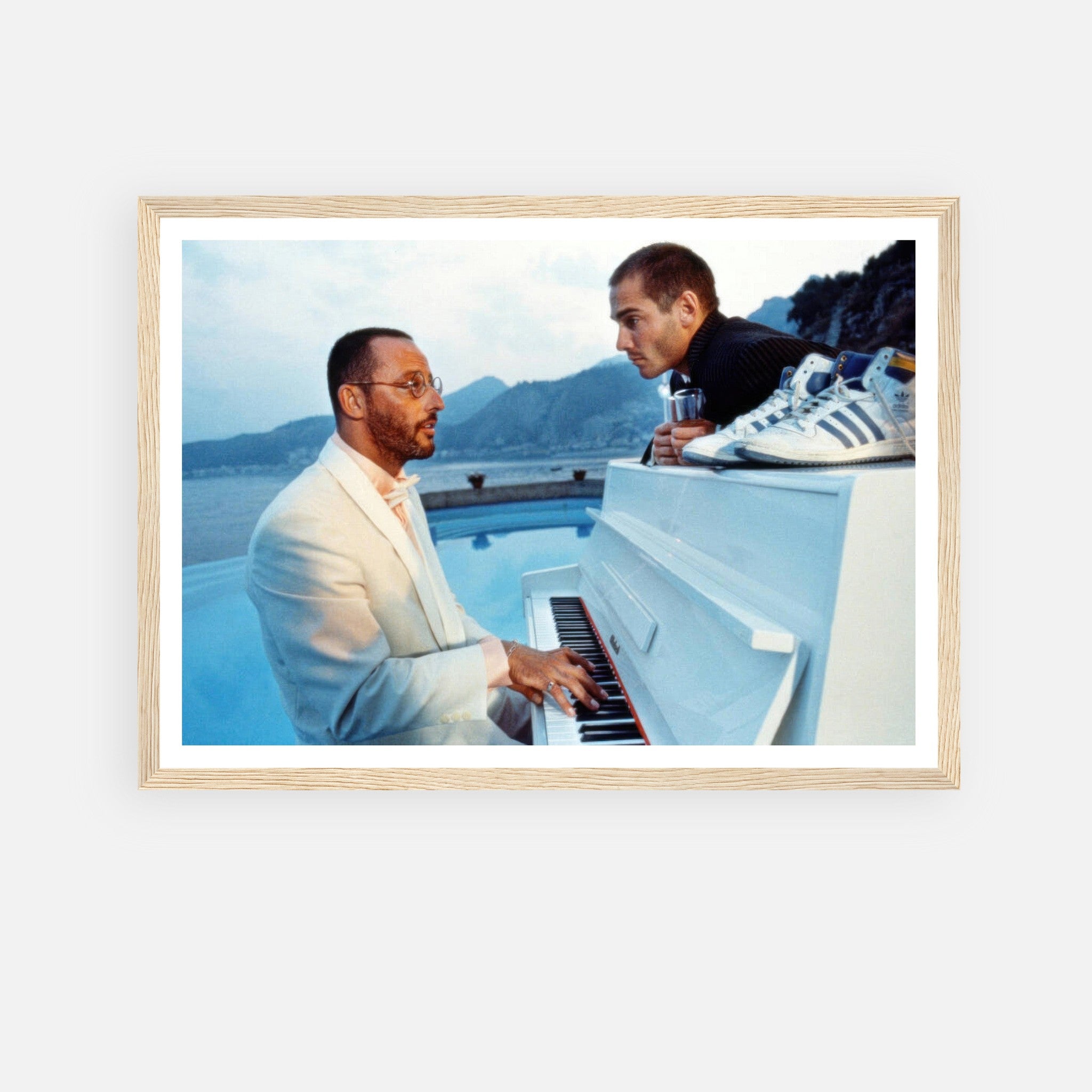 Jean Reno playing piano, iconic scene from "The Big Blue," framed print with serene ocean and mountain backdrop.